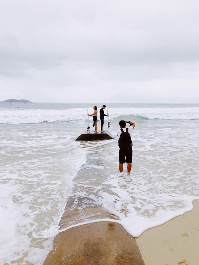 Couple with surfboards getting photographed standing back to back