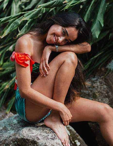 photo of smiling woman sitting on rock