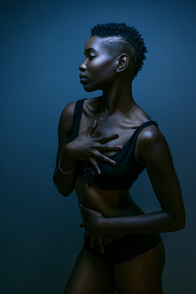 Boudoir portrait with dramatic blue lighting and sculptural pose, evoking a fine art aesthetic