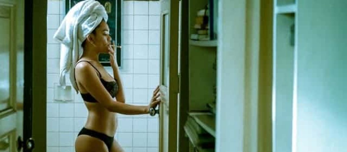 Asian woman in black bra and panties smoking a cigarette in bathroom