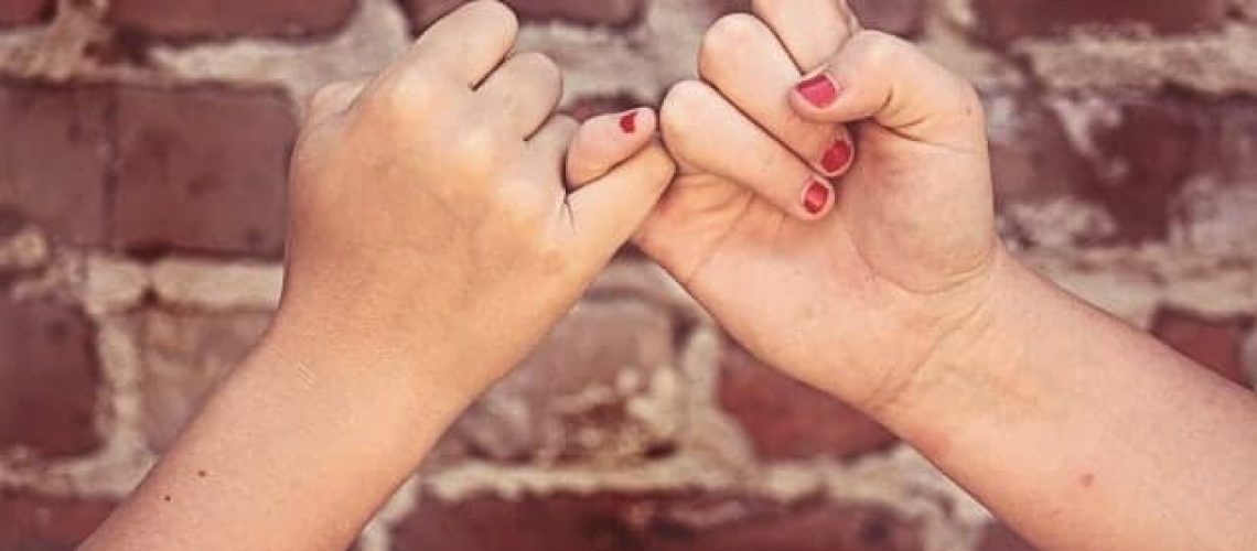 Pinky promise against brick wall